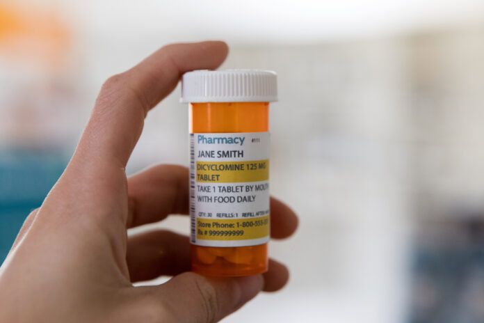 Prescription medication container being held in hand