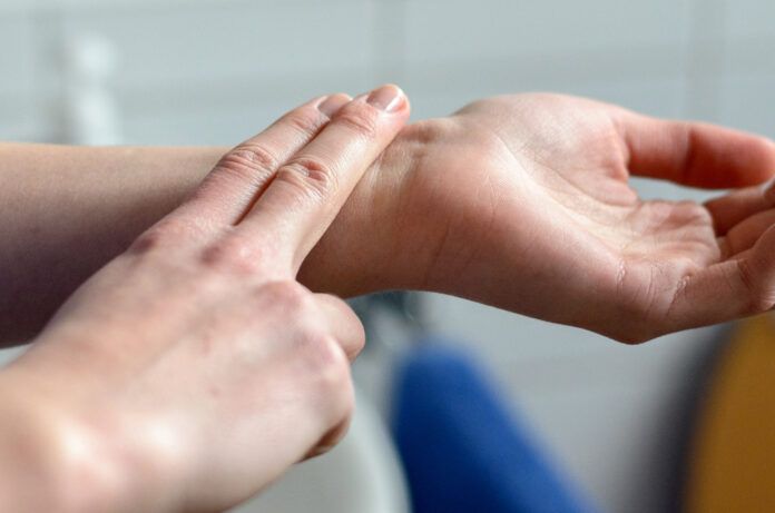 Hands of a woman checking her pulse