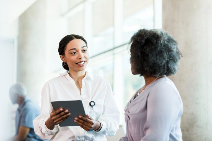 As businesswoman speaks, therapist updates electronic medical record on tablet